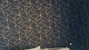 A bed with white bedding, a geometric patterned wall behind it, and a small bedside table with a lamp. - Charming 1 Bed Condo, Only 15 Minute Walk to Downtown (Salt Lake City)