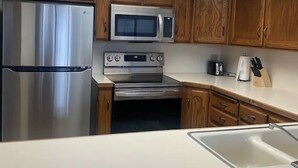A modern kitchen with wooden cabinets, stainless steel appliances, and a skylight. - Charming 1 Bed Condo, Only 15 Minute Walk to Downtown (Salt Lake City)