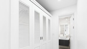 A hallway with white doors and a bathroom with a sink and mirror. - Indigo Oceanfront Condo Middle Floor - Unit 2, Indigo Oceanview Terrace 2 (Sint Maarten)