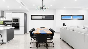 A modern kitchen with a central island, a dining table with chairs, and a white sofa. - Indigo Oceanfront Condo Middle Floor - Unit 2, Indigo Oceanview Terrace 2 (Sint Maarten)