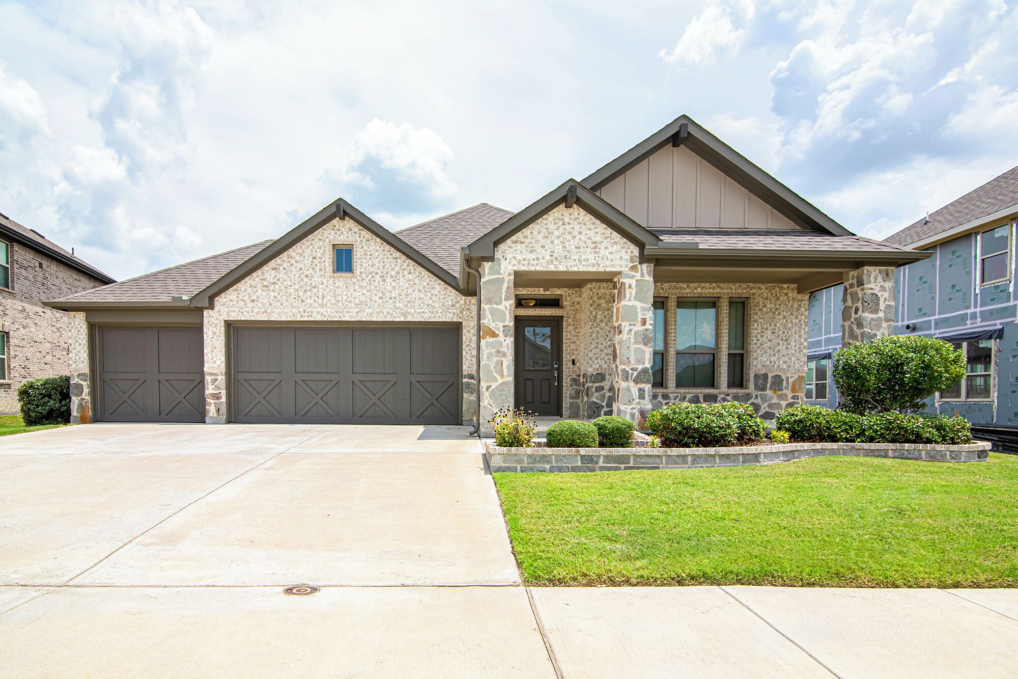 A residential house with a stone facade, two garages, and a well-maintained lawn.
