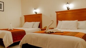 Two double beds with wooden headboards, white linens, and decorative swan pillows.