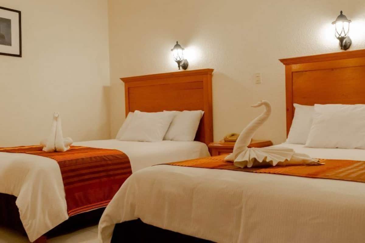 Two double beds with wooden headboards, white linens, and decorative swan pillows.