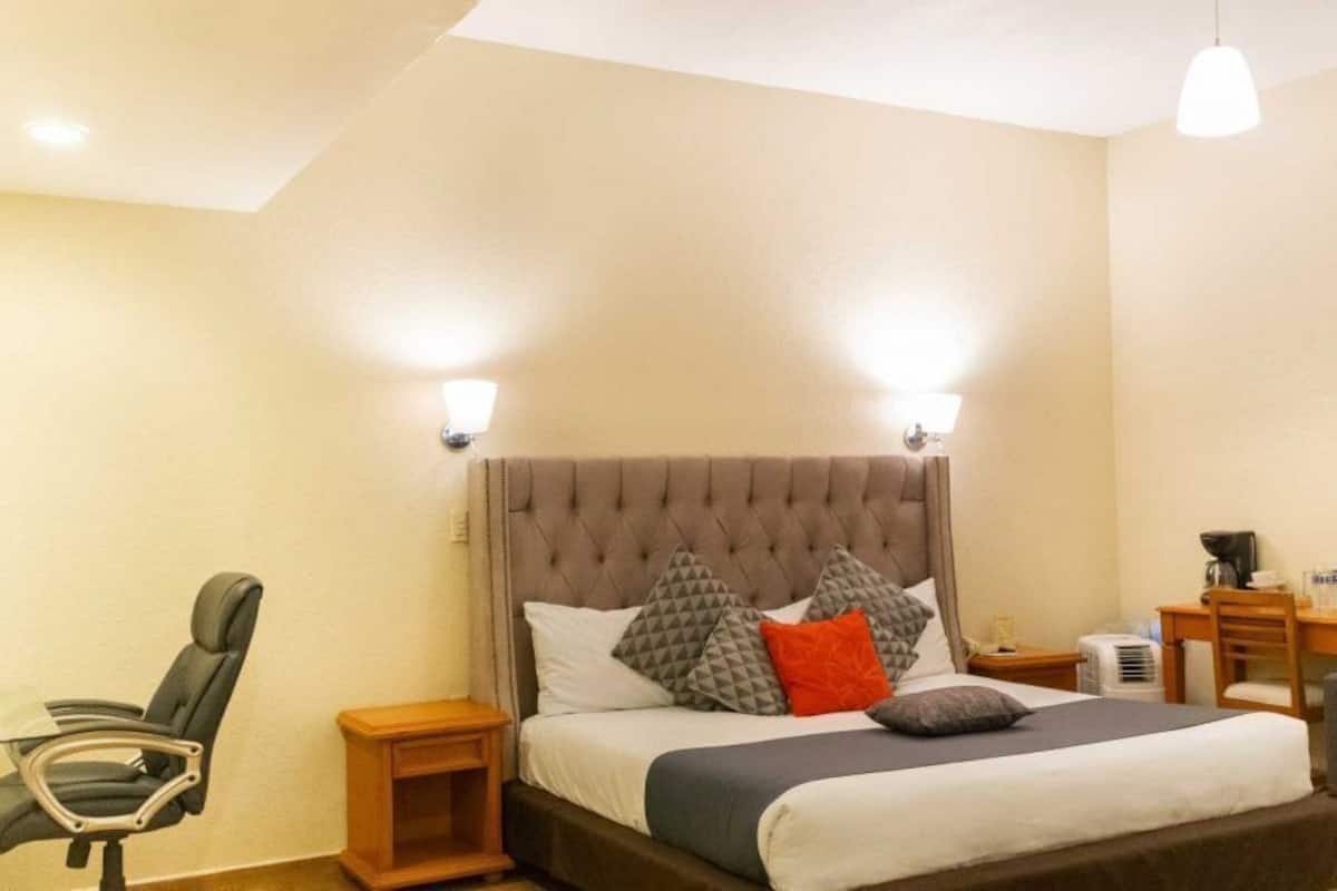 A hotel room with a bed, a desk, a chair, and a couch.