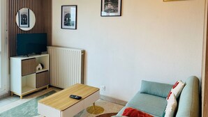 A modern living room with a flat-screen TV, a sofa, a coffee table, and framed pictures on the wall.