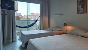 A hotel room with two beds, a hammock, a lamp, and a TV on the wall. - Lindo Apartamento na Praia do Forte! (204) (Cabo Frio)