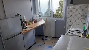 A compact kitchen with a refrigerator, stove, and a window providing natural light.