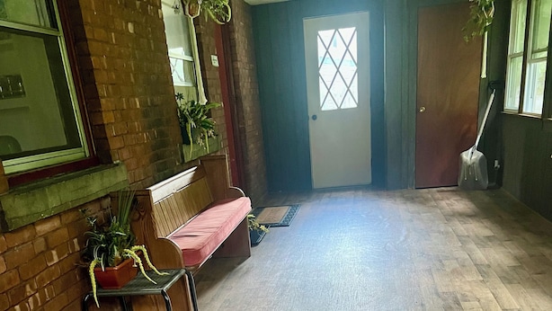 Un couloir avec un plancher en bois, un banc et des plantes en pot.