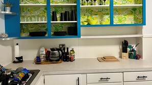 Une cuisine aux couleurs bleu et blanc, avec un meuble décoratif contenant de la verrerie et de la vaisselle.