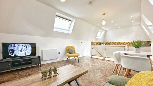 A modern living room with a television, seating, a dining area, and a kitchen in the background. - Luxurious house in central Cambridge  (Cambridge)