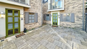 A modern building with a stone facade, a green door, and a balcony with a glass railing. - Luxurious house in central Cambridge  (Cambridge)