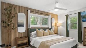 A bedroom with a bed, bedside table, lamp, and a large window with curtains. - Charming 3-bedroom house with AC and WiFi. LAKE ACCESS King Beds! Newly Remodel (Minneapolis)