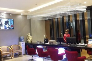 A reception area with a counter, chairs, a television, and a decorative sculpture. - Juli Boutique Hotel (Kunming Jinma Zhengchang Fruit Market Juhua Subway Station) (Kunming)