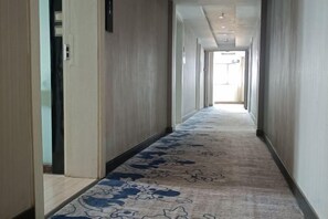 A hallway with a patterned carpet, doors on both sides, and a light source at the end. - Juli Boutique Hotel (Kunming Jinma Zhengchang Fruit Market Juhua Subway Station) (Kunming)