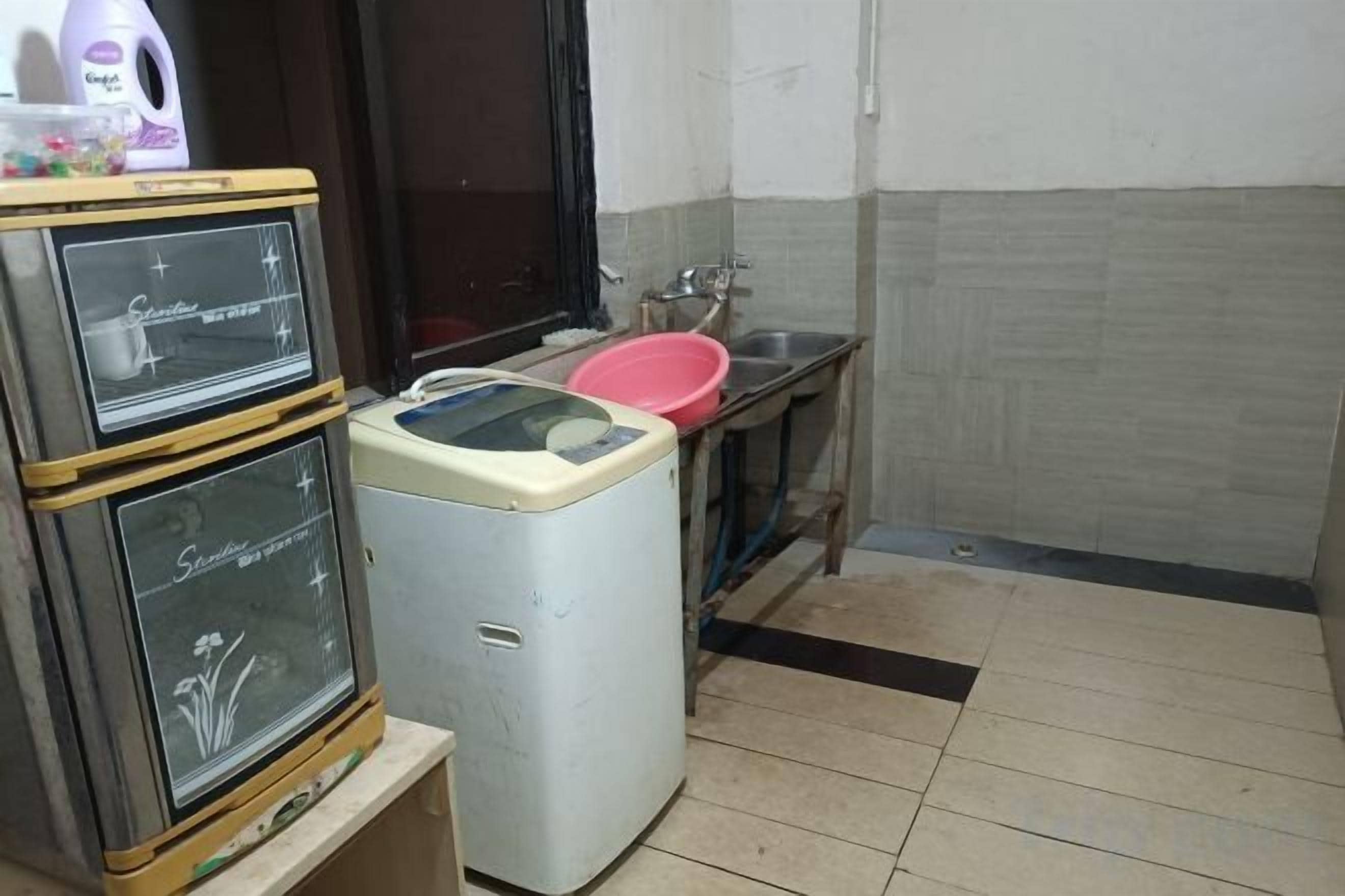 Cocina compacta con lavadora, lavamanos y una pequeña encimera.