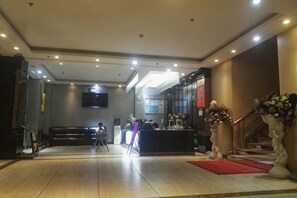 A hotel lobby with a reception desk, a staircase, and a flat-screen TV mounted on the wall. - Juli Boutique Hotel (Kunming Jinma Zhengchang Fruit Market Juhua Subway Station) (Kunming)