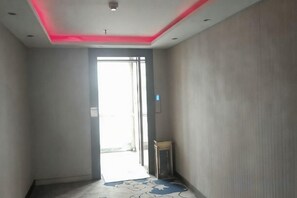 A hallway with a door leading to a bright area, a small table, and a patterned rug. - Juli Boutique Hotel (Kunming Jinma Zhengchang Fruit Market Juhua Subway Station) (Kunming)
