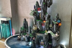 A rock garden with a pond, featuring a waterfall and various decorative elements. - Juli Boutique Hotel (Kunming Jinma Zhengchang Fruit Market Juhua Subway Station) (Kunming)