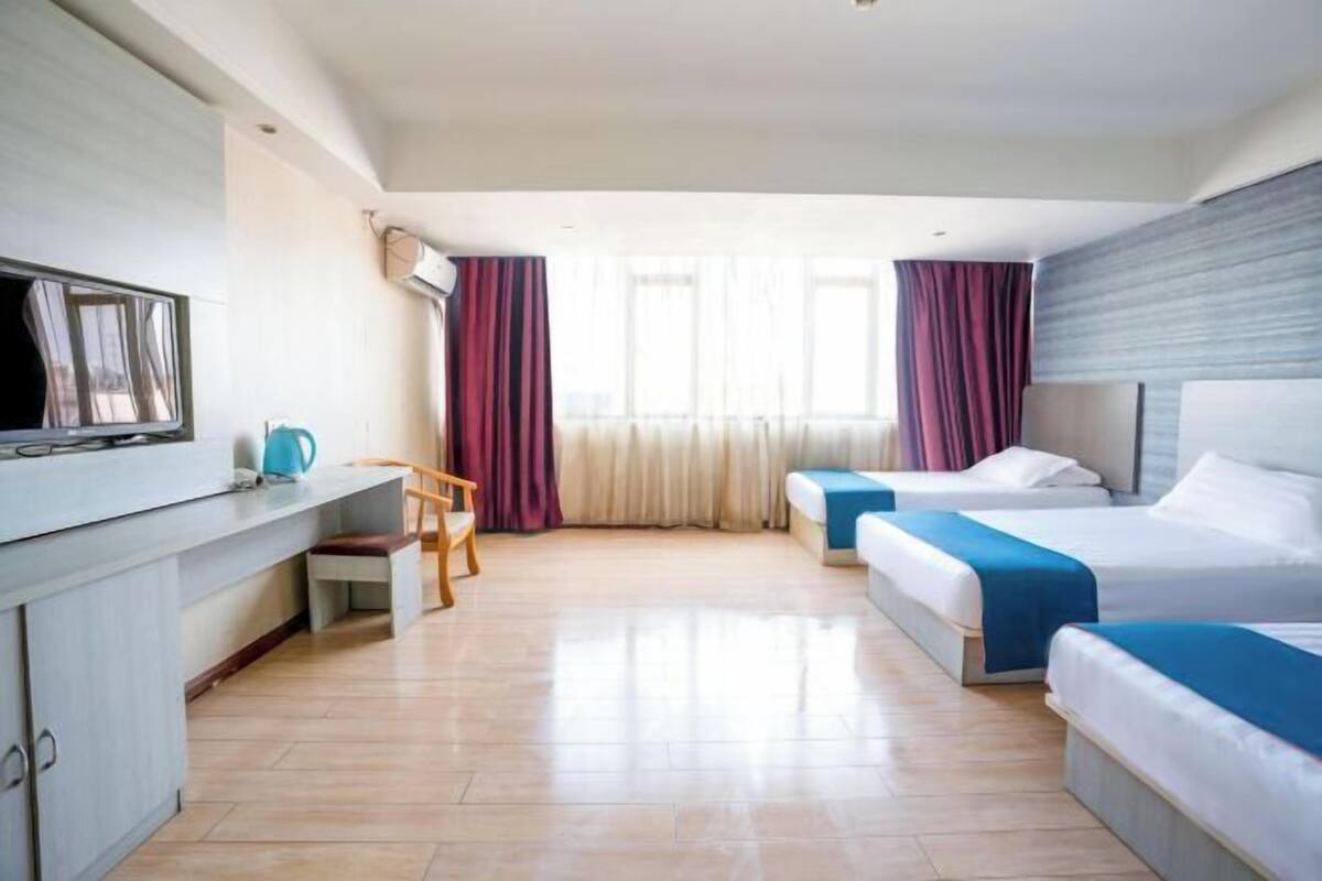 A hotel room with a bed, bedside tables, a desk, a chair, and a television.