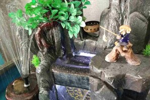 A miniature waterfall with a decorative figure and a plant. - Juli Boutique Hotel (Kunming Jinma Zhengchang Fruit Market Juhua Subway Station) (Kunming)