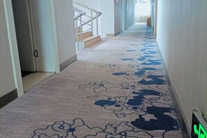 A carpeted hallway with a patterned design, a handrail, and a door on the left. - Juli Boutique Hotel (Kunming Jinma Zhengchang Fruit Market Juhua Subway Station) (Kunming)