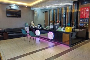 A reception area with a counter, chairs, and a large mirror. - Juli Boutique Hotel (Kunming Jinma Zhengchang Fruit Market Juhua Subway Station) (Kunming)