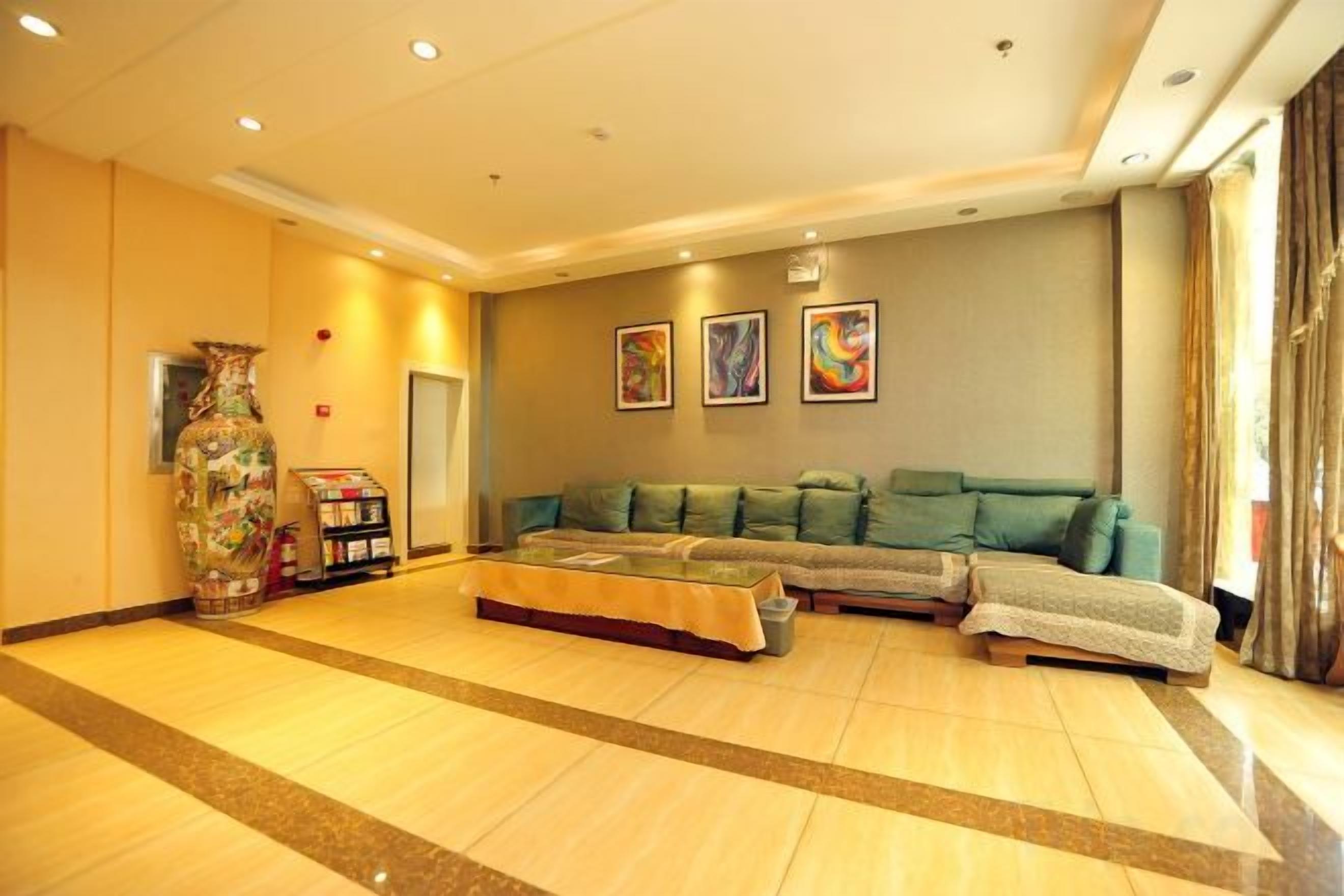 A spacious room with a large sofa, a decorative vase, and artwork on the wall.