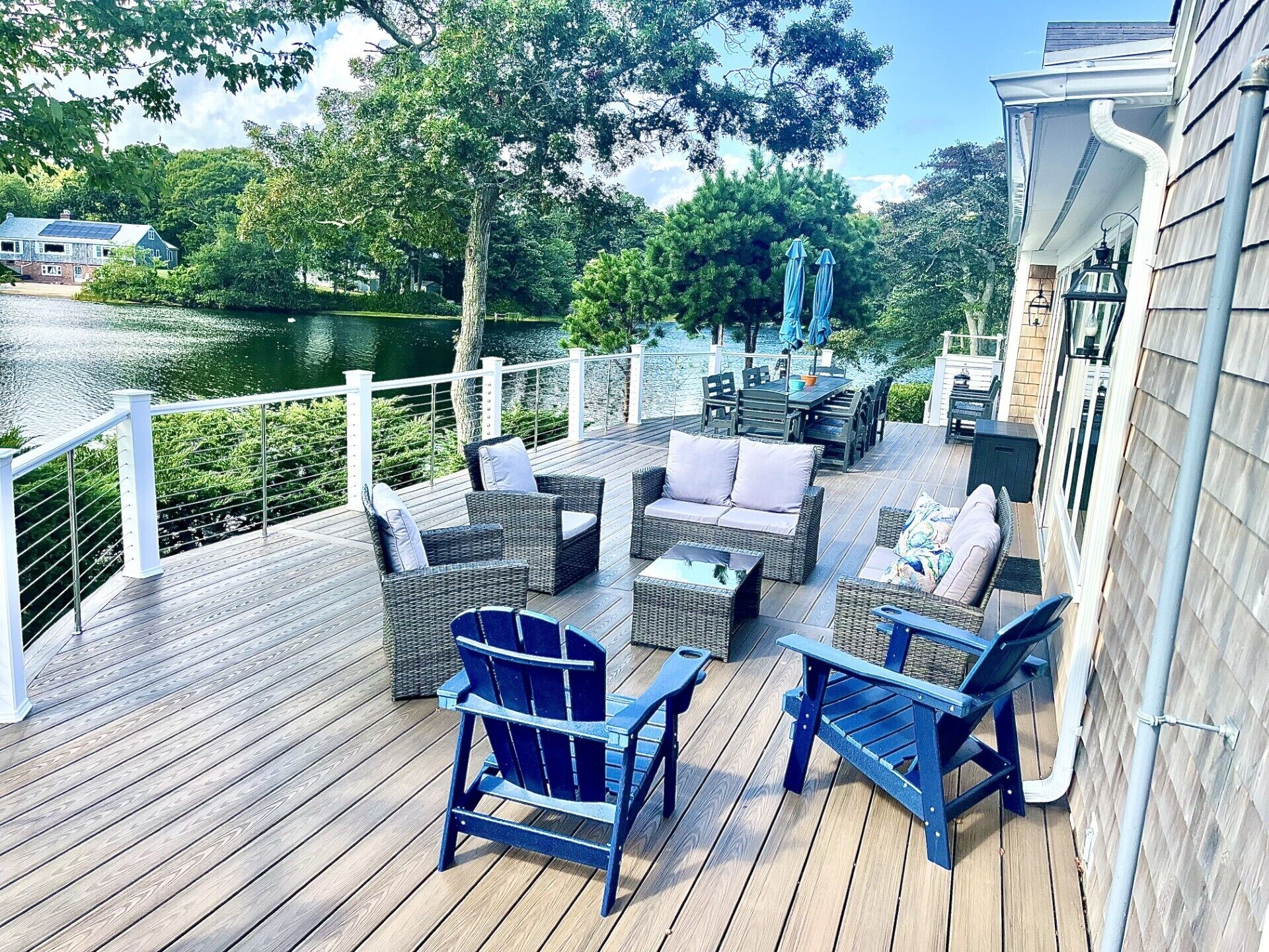 A wooden deck with outdoor furniture, a view of a lake, and a white railing.