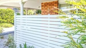 A residential property with a white fence, a brick wall, and a covered porch area. - Private Pool | Sleeps 12 | Pets | Basketball Hoop (Coffs Harbour)