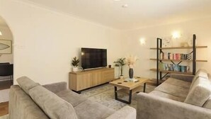 A living room with a sofa set, a coffee table, a TV, and a bookshelf. - Private Pool | Sleeps 12 | Pets | Basketball Hoop (Coffs Harbour)