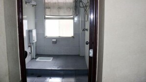 A small, tiled bathroom with a window, a toilet, and a shower area. - Danjiangkou Xinlong Hotel (Danjiangkou)