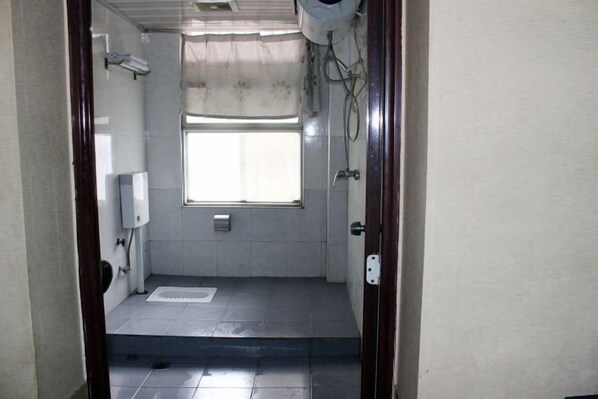 A small, tiled bathroom with a window, a toilet, and a shower area. - Danjiangkou Xinlong Hotel (Danjiangkou)