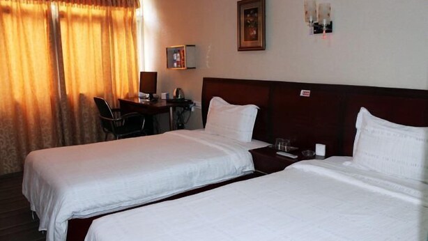 A hotel room with two beds, a desk, and a chair. - Danjiangkou Xinlong Hotel (Danjiangkou)