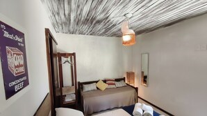 A hotel room with a bed, a bedside table, a hanging light fixture, and a poster on the wall. - Gambá Casa Boutique (Búzios)