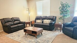 A living room with two black leather sofas, a wooden coffee table, and a patterned rug. - Spacious 4-bedroom single level house with  RV parking in Jurupa Valley (Jurupa Valley)