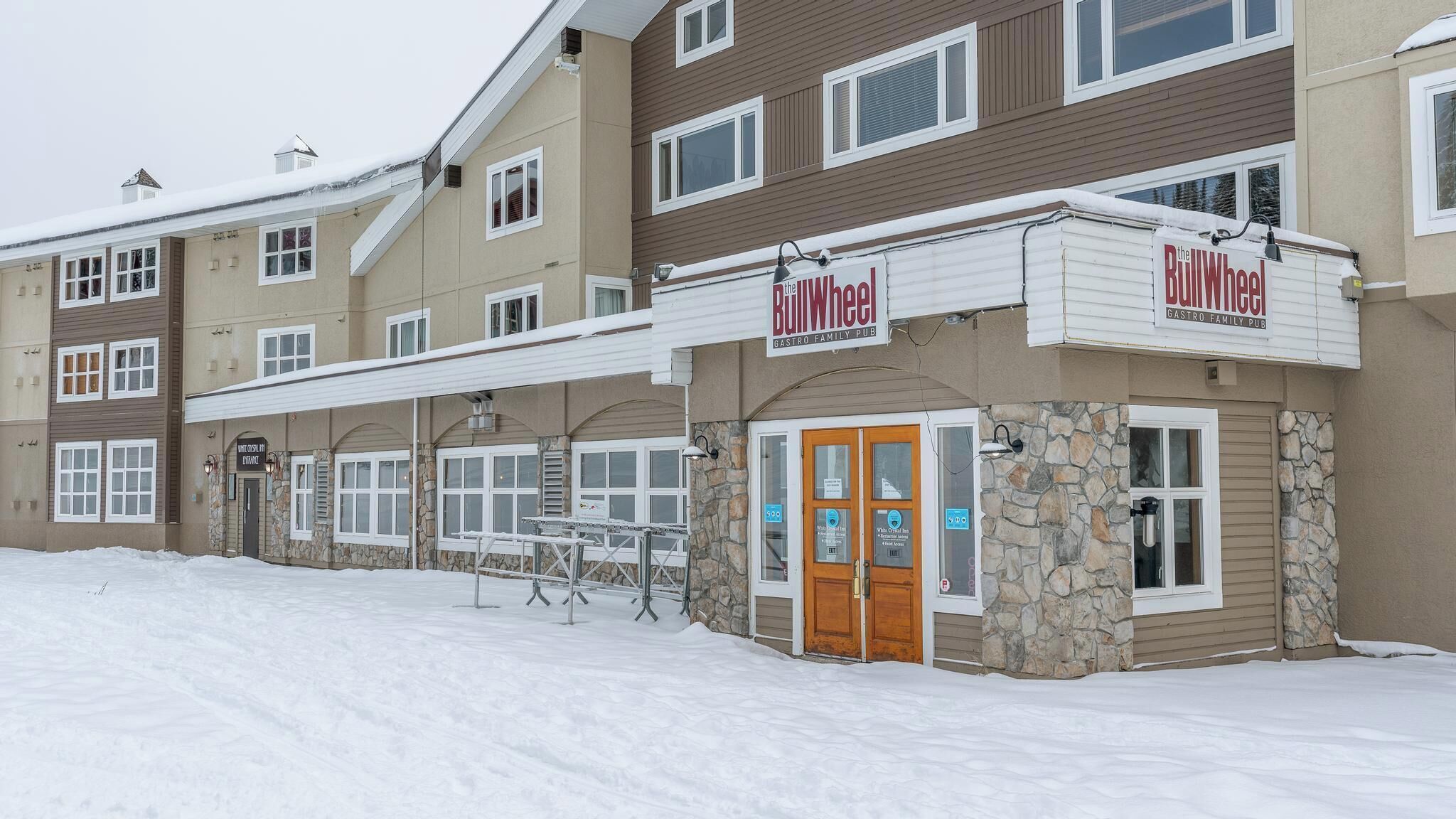 Un immeuble dont le rez-de-chaussée abrite un restaurant appelé « The BullWheel », caractérisé par une façade en pierre et une porte en bois.