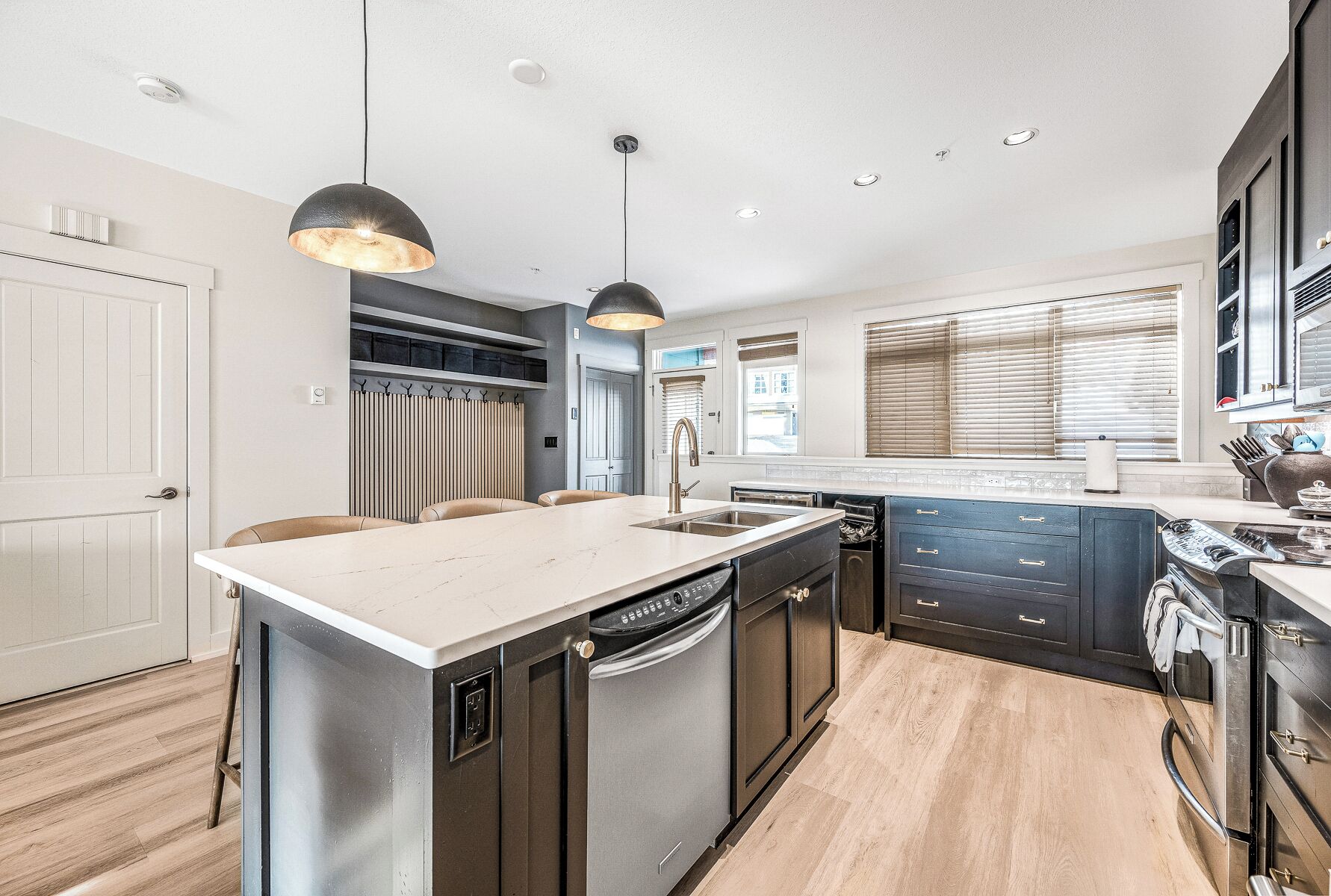 A modern kitchen with a central island, built-in appliances, and pendant lighting.