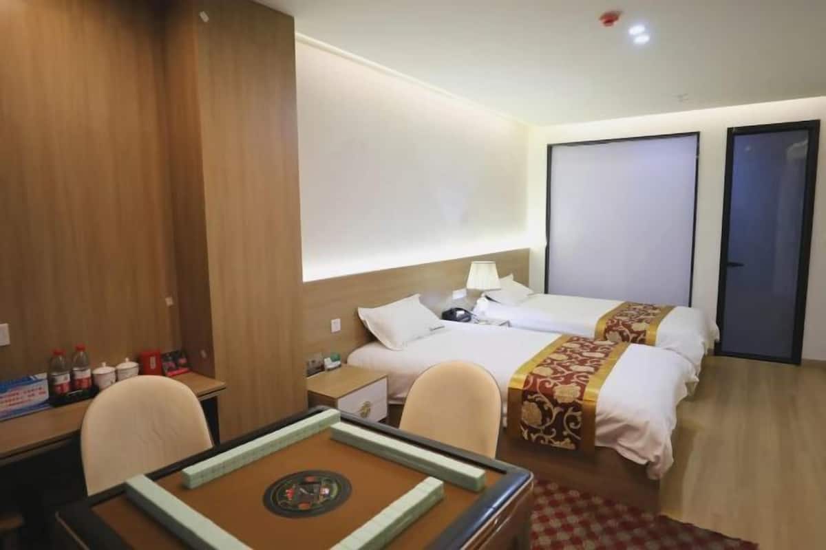 Une chambre d’hôtel avec deux lits, un bureau avec un jeu de société, une chaise et une petite table.