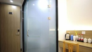 Une pièce avec une porte en bois, une cloison en verre, un bureau en bois et une chaise.