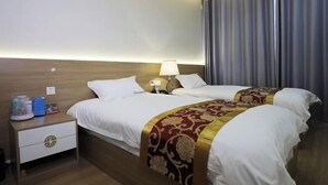 Une chambre d’hôtel avec deux lits, une table de chevet, une lampe et un rideau.