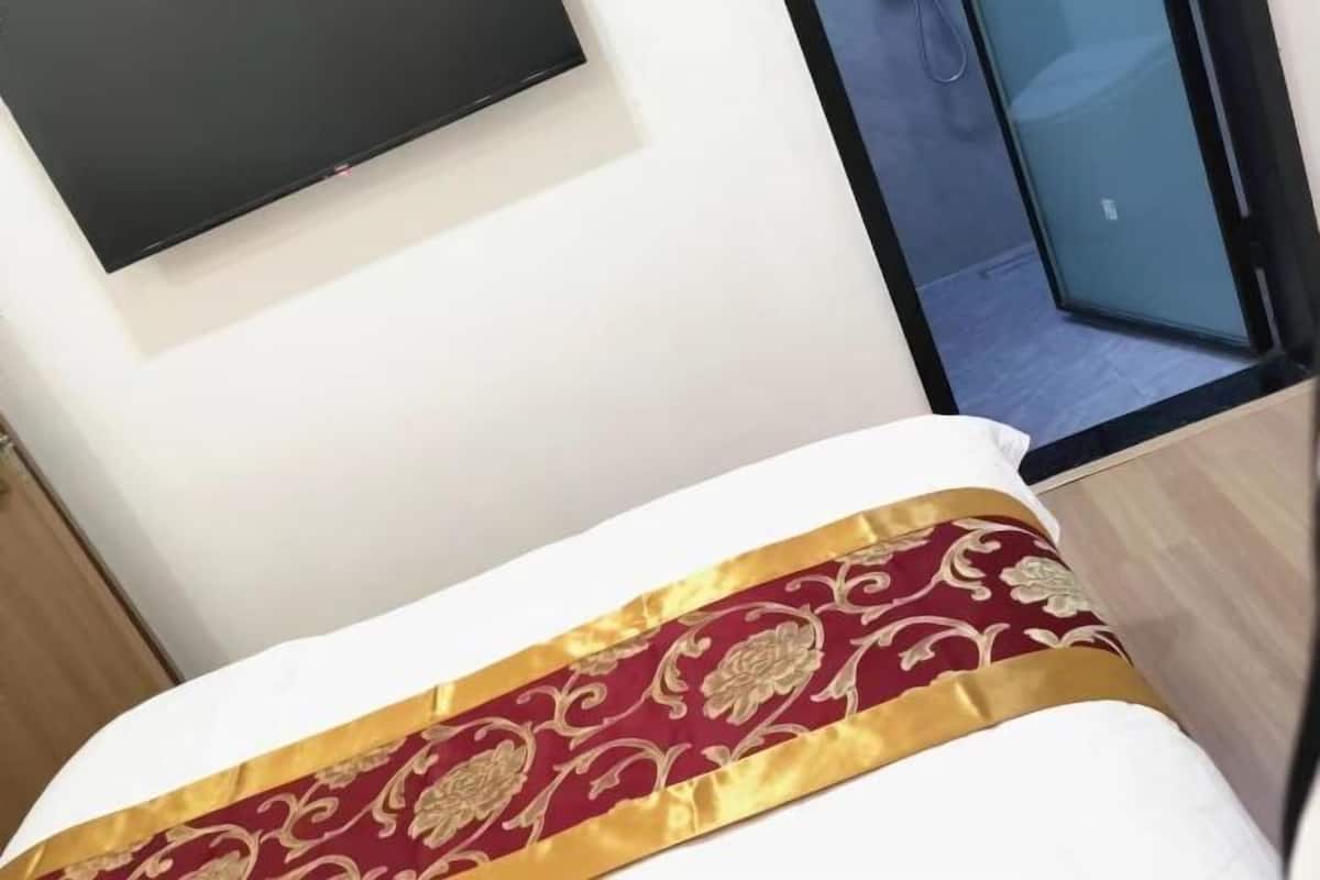 Une chambre d’hôtel avec un lit, un téléviseur fixé au mur et une vue sur l’extérieur par une fenêtre.