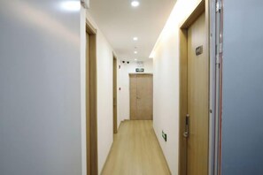 A narrow hallway with wooden flooring, doors on both sides, and a ceiling with recessed lighting. - FuNan Baijing Shangwu Hotel (Funan)