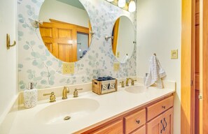 Ein Badezimmer mit zwei Waschbecken, einer Holzwaschmöbeln und einem Spiegel mit floralem Wandpapier.