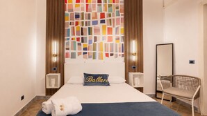Een hotelkamer met een bed, een stoel, een kunstwerk aan de muur en een spiegel.