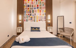 Une chambre d’hôtel avec un lit, une chaise, une œuvre d’art murale et un miroir.