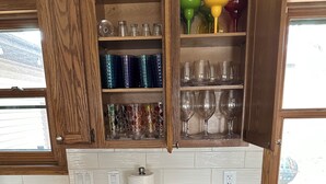 A kitchen with wooden cabinets, a granite countertop, a dish rack, and a drawer with utensils. - Harmony House, spacious 5-bedrooms in downtown Baraboo near Devil's Lake Park (Baraboo)