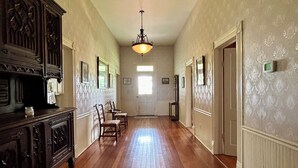 A hallway with wooden flooring, a chandelier, and a door at the end.
