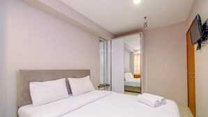 A hotel room with a bed, a television mounted on the wall, and a mirror. - Good And Comfy 2Br Cinere Bellevue Suites Apartment (Depok)