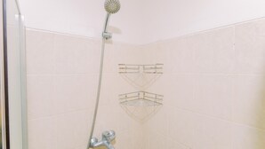 A shower area with a handheld showerhead, a wall-mounted faucet, and two corner-mounted towel racks. - Homey And Big Studio Apartment At The Wave Kuningan (Jakarta)