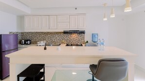 A modern kitchen with white cabinets, a large island, a purple refrigerator, and pendant lights. - Homey And Big Studio Apartment At The Wave Kuningan (Jakarta)